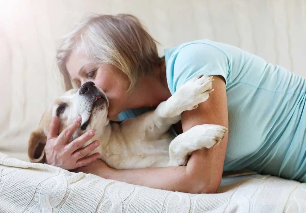 Older woman hugging her senior dog